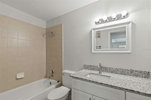 full bathroom with vanity, toilet, a textured ceiling, and tiled shower / bath combo