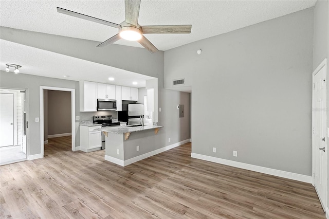 kitchen with white cabinetry, stainless steel appliances, kitchen peninsula, and light hardwood / wood-style flooring