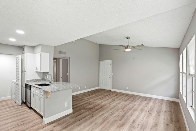 kitchen featuring lofted ceiling, white cabinets, dishwasher, sink, and light wood-type flooring