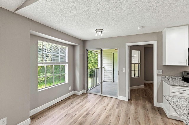 dining area featuring light wood-type flooring and a textured ceiling