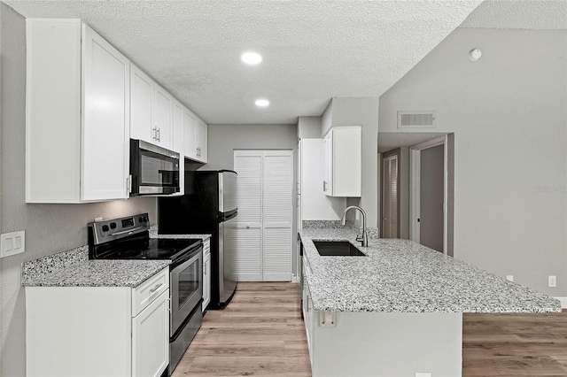 kitchen featuring appliances with stainless steel finishes, sink, white cabinets, light stone countertops, and light hardwood / wood-style flooring