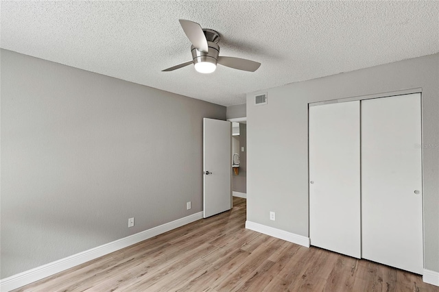 unfurnished bedroom featuring a textured ceiling, light wood-type flooring, ceiling fan, and a closet