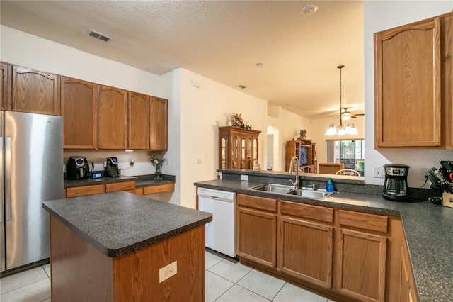 kitchen featuring stainless steel refrigerator, dishwasher, a textured ceiling, a center island, and sink