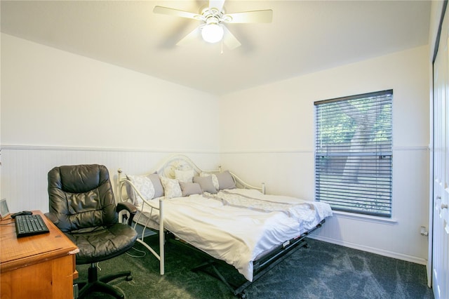 bedroom featuring wooden walls, dark colored carpet, and ceiling fan