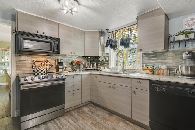 kitchen featuring black appliances, plenty of natural light, wood-type flooring, and sink