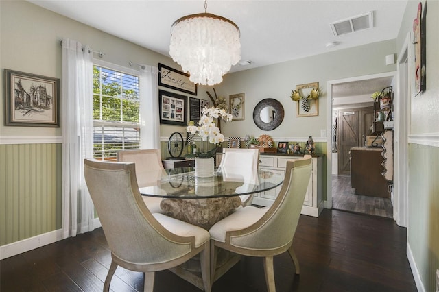 dining area featuring dark wood-type flooring and an inviting chandelier