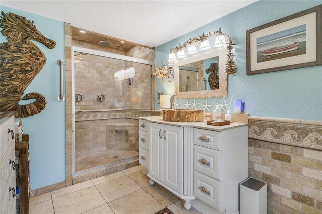 bathroom with a textured ceiling, vanity, tile patterned floors, and a shower with shower door