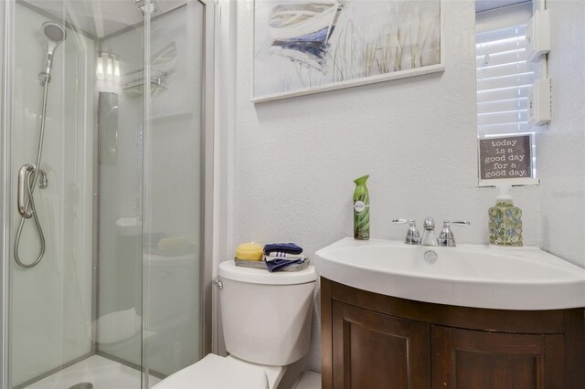 bathroom with vanity, a shower with shower door, and toilet