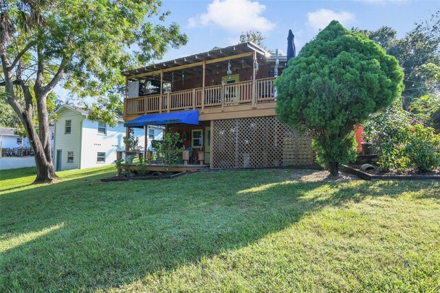 rear view of property featuring a lawn and a deck