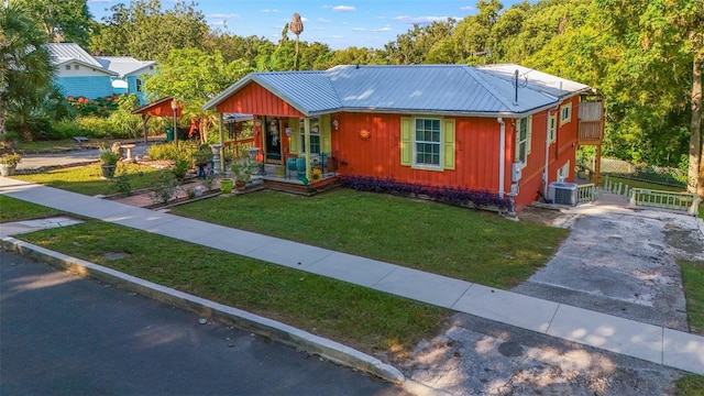 view of front of property featuring central AC unit, covered porch, and a front yard