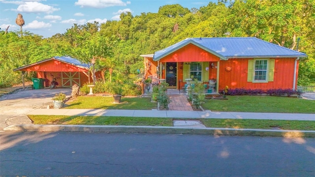 view of front of house featuring driveway, metal roof, and a front lawn