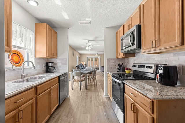 kitchen featuring a textured ceiling, appliances with stainless steel finishes, and light hardwood / wood-style floors