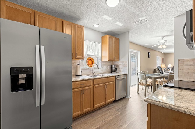 kitchen featuring ceiling fan, sink, light hardwood / wood-style flooring, backsplash, and appliances with stainless steel finishes