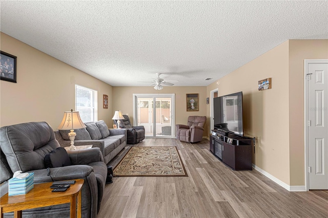 living room with light hardwood / wood-style flooring, ceiling fan, and a textured ceiling