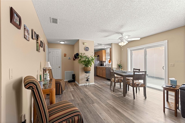 dining room with ceiling fan, a textured ceiling, and light wood-type flooring