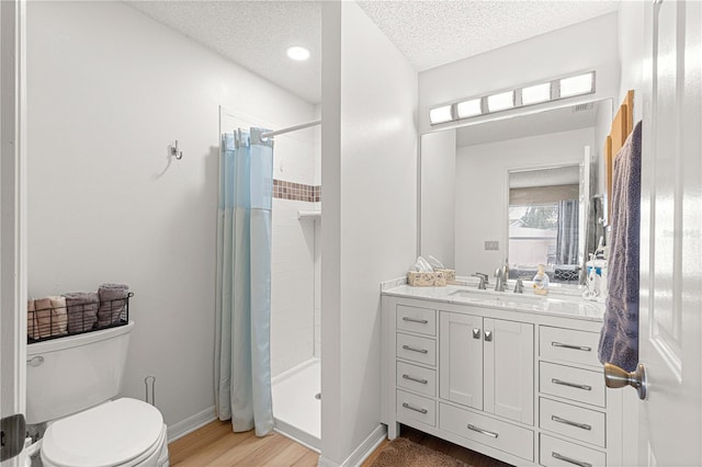 bathroom with vanity, walk in shower, a textured ceiling, toilet, and hardwood / wood-style floors