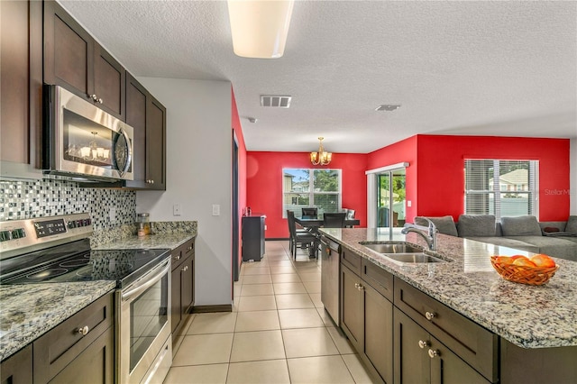 kitchen with light tile patterned floors, sink, a textured ceiling, a chandelier, and appliances with stainless steel finishes