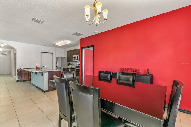 dining area with an inviting chandelier, a textured ceiling, and light tile patterned floors