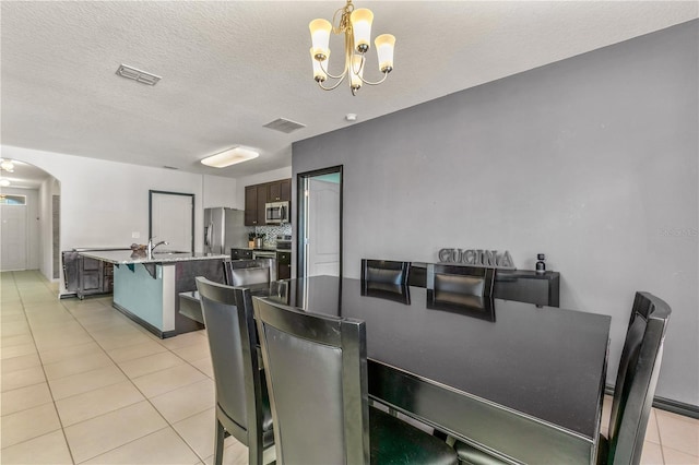 dining area featuring an inviting chandelier, a textured ceiling, sink, and light tile patterned flooring