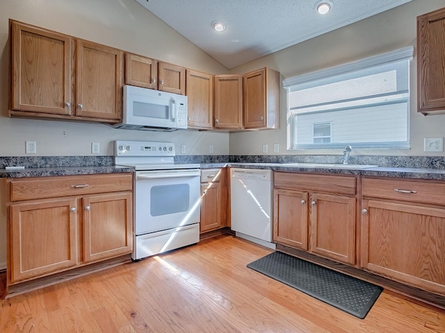 kitchen with vaulted ceiling, white appliances, a textured ceiling, light hardwood / wood-style flooring, and sink