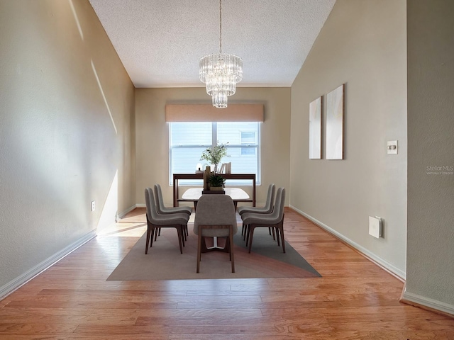 dining room featuring light wood-type flooring, lofted ceiling, and an inviting chandelier