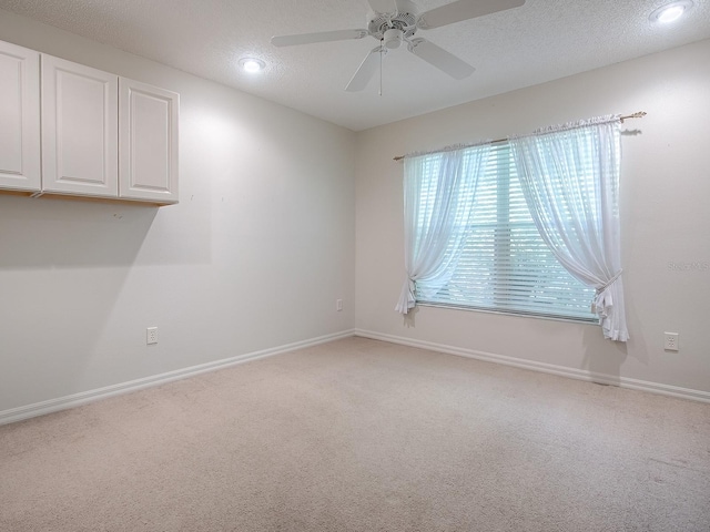 carpeted empty room featuring ceiling fan and a textured ceiling