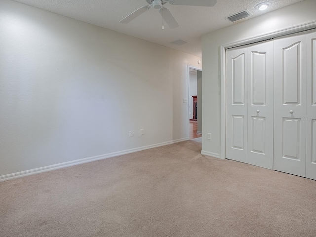 unfurnished bedroom with ceiling fan, light colored carpet, a textured ceiling, and a closet