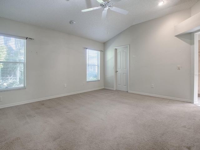 carpeted spare room featuring a textured ceiling, lofted ceiling, and ceiling fan