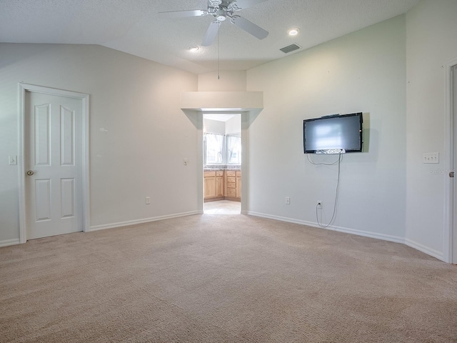 unfurnished living room with a textured ceiling, vaulted ceiling, ceiling fan, and light colored carpet