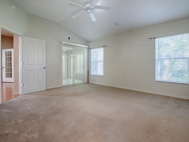 carpeted spare room featuring ceiling fan, plenty of natural light, and vaulted ceiling