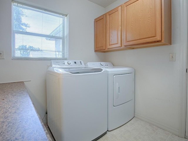 clothes washing area featuring washing machine and clothes dryer and cabinets