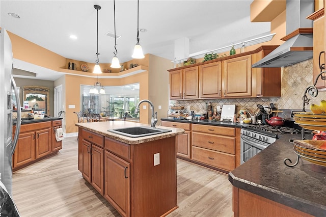 kitchen featuring decorative backsplash, light hardwood / wood-style floors, an island with sink, pendant lighting, and sink