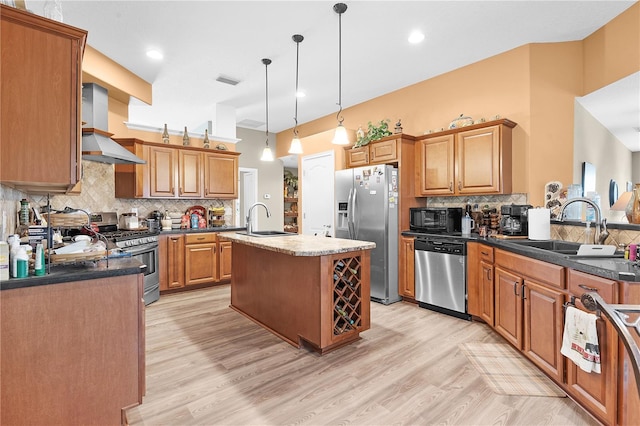 kitchen with sink, decorative light fixtures, a kitchen island with sink, wall chimney exhaust hood, and appliances with stainless steel finishes