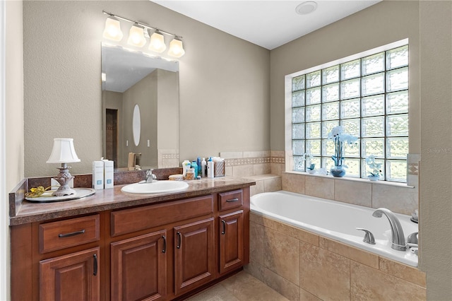 bathroom featuring tiled tub and vanity