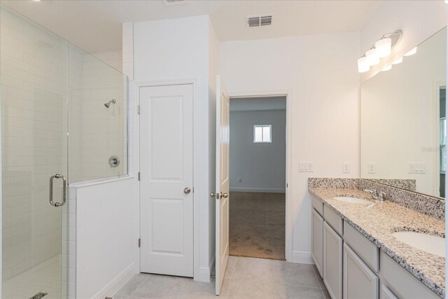 bathroom with tile patterned flooring, vanity, and a shower with door