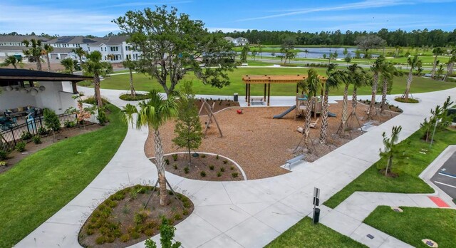 view of community featuring a water view, a playground, and a yard