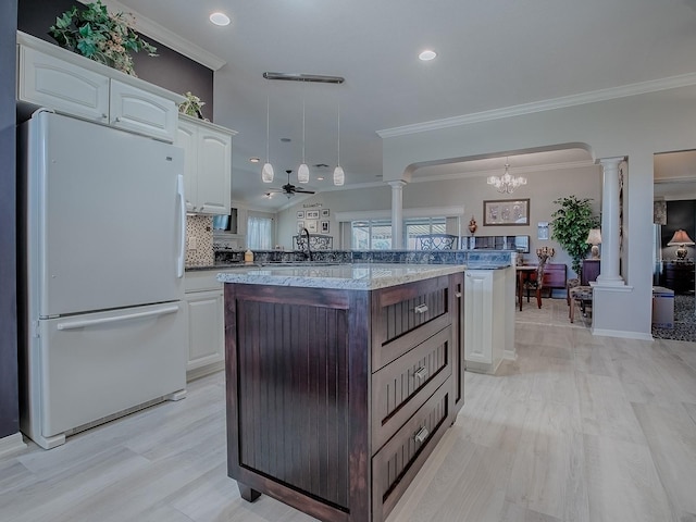 kitchen featuring white cabinetry, white fridge, hanging light fixtures, and decorative columns