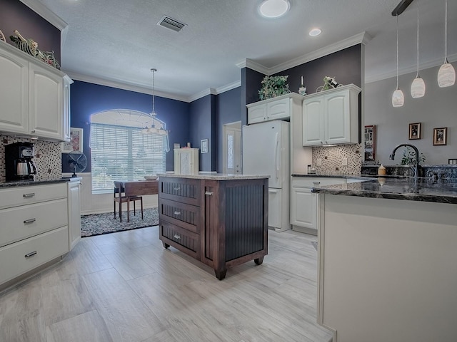 kitchen featuring dark stone countertops, white cabinets, white fridge, and decorative light fixtures