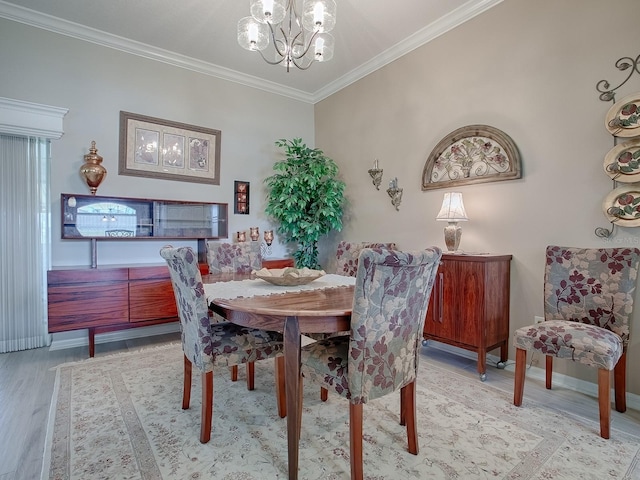 dining area with light hardwood / wood-style floors, crown molding, and a chandelier