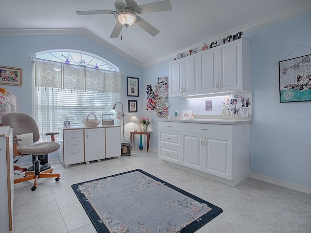 interior space with light tile patterned flooring, white cabinetry, ceiling fan, vaulted ceiling, and crown molding