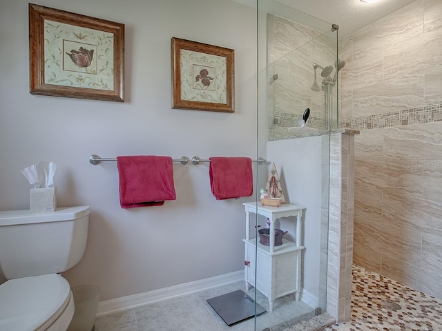 bathroom with tile patterned floors, a tile shower, and toilet