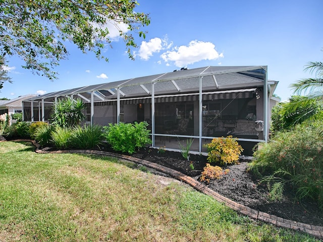 rear view of house with a lanai and a lawn