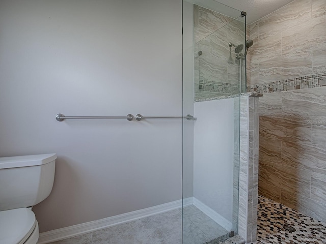 bathroom with tile patterned flooring, toilet, and tiled shower