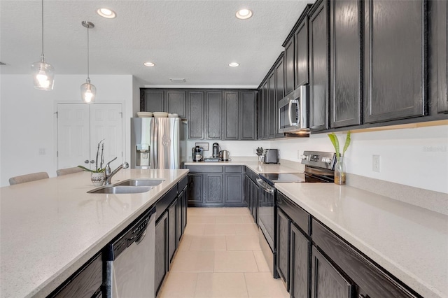 kitchen featuring pendant lighting, a textured ceiling, sink, stainless steel appliances, and light tile patterned floors