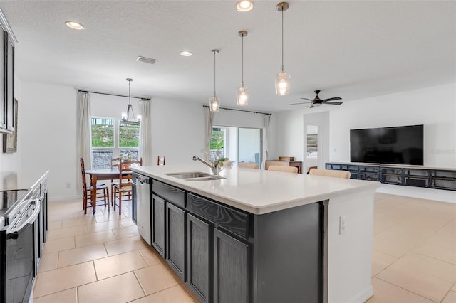 kitchen featuring ceiling fan with notable chandelier, a kitchen island with sink, plenty of natural light, and sink