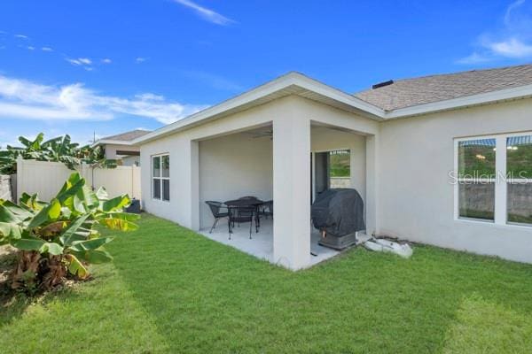 rear view of property featuring a lawn and a patio area