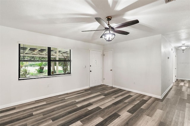 unfurnished room with dark hardwood / wood-style flooring, ceiling fan with notable chandelier, and a textured ceiling