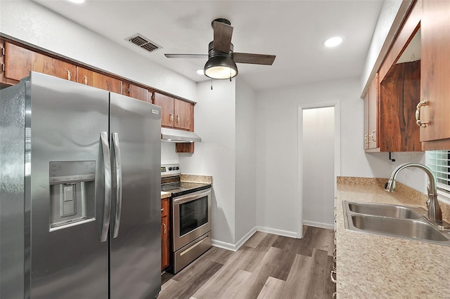 kitchen with appliances with stainless steel finishes, light hardwood / wood-style flooring, ceiling fan, and sink