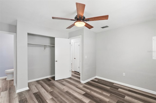 unfurnished bedroom featuring a closet, ceiling fan, dark hardwood / wood-style flooring, and ensuite bath