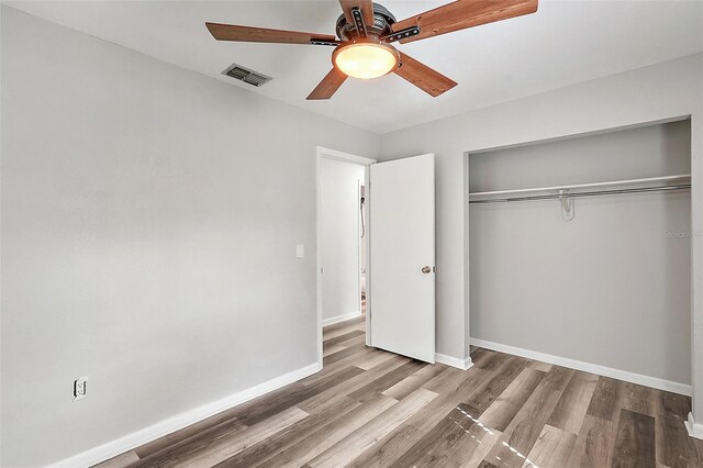 unfurnished bedroom with ceiling fan, wood-type flooring, and a closet